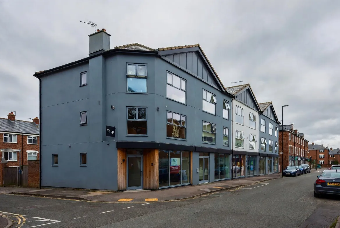 Modern grey corner building with large commercial windows.