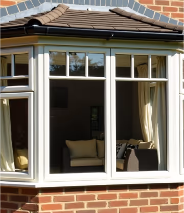  A white bay window with multiple glass panels on a brick house.